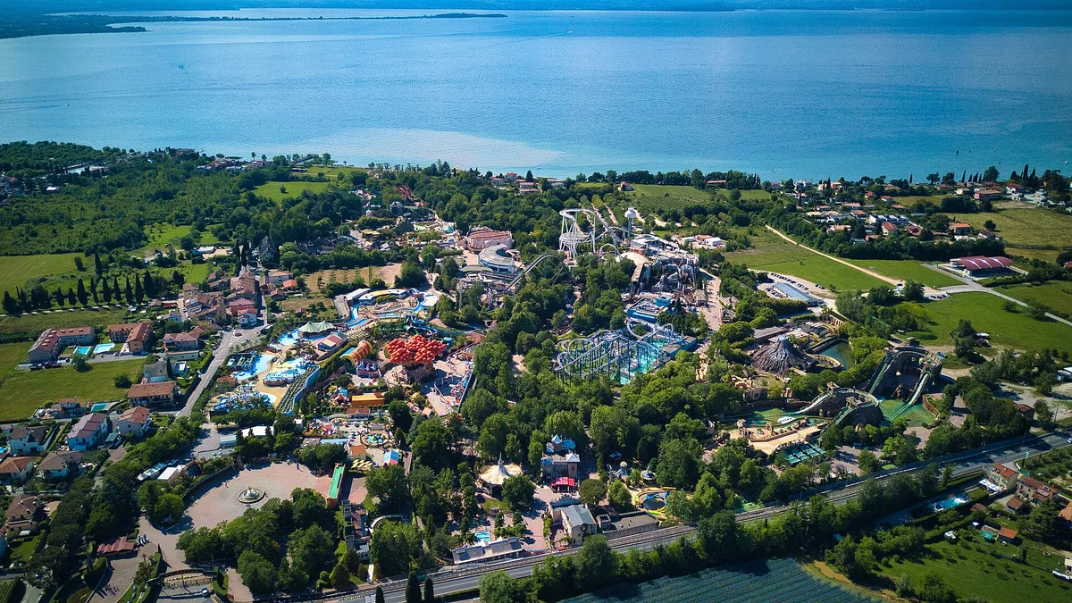 Gardaland vista dall'alto, con le attrazioni tra il verde e il Lago di Garda sullo sfondo